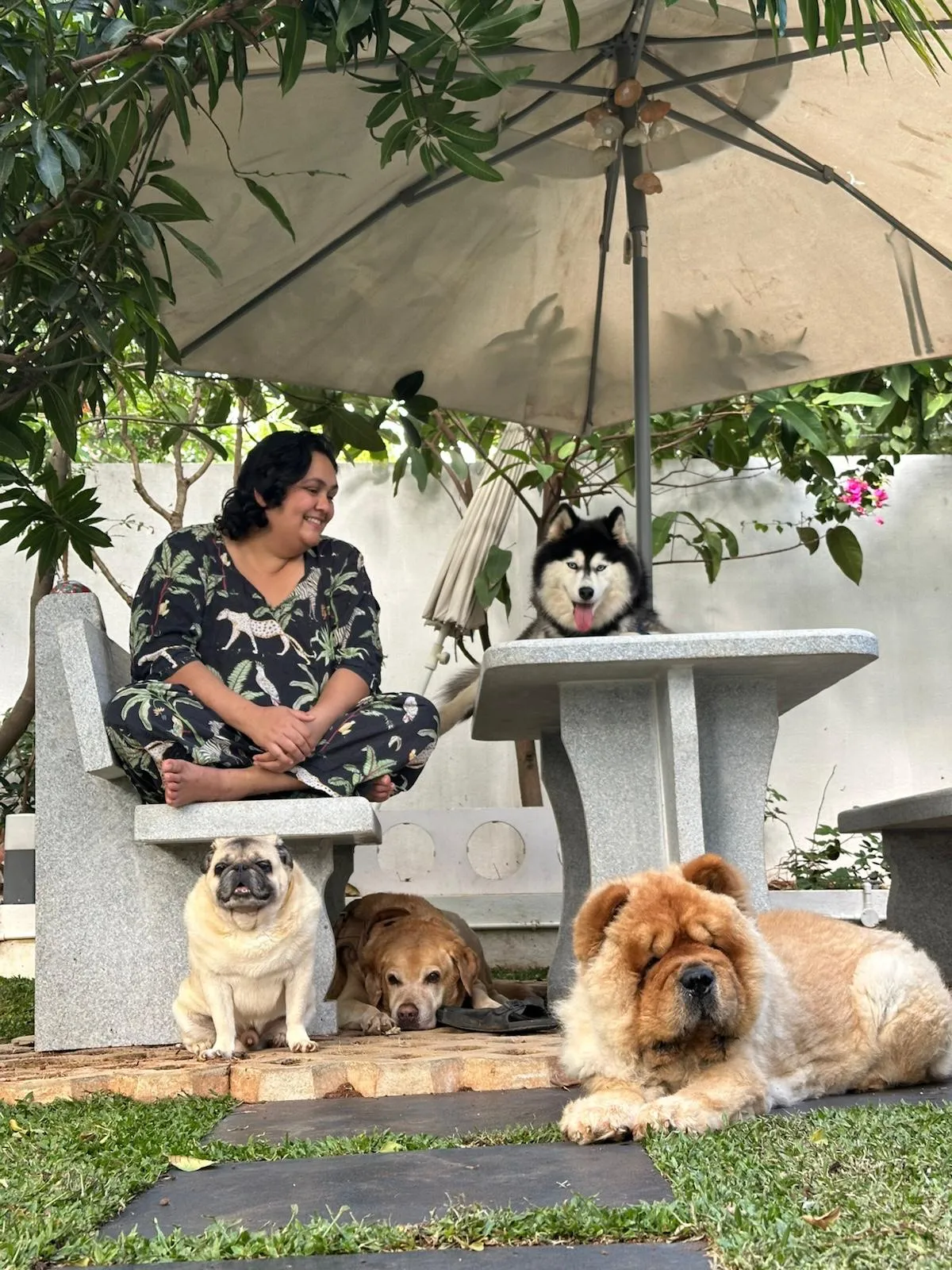 Muktai sitting in her garden at Meraki with her dogs Mizu, Muffin, Momo and Berlin